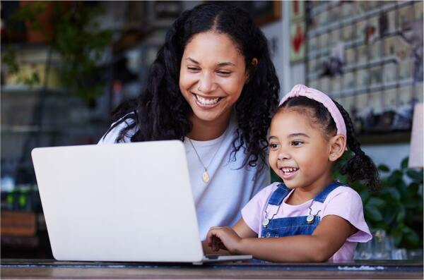 a woman and a child smiling and looking at laptop screen